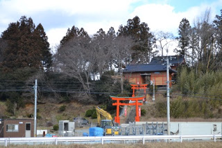 間隔をあけて2つの朱色の鳥居が並ぶ斜面の階段の先に、木々に囲まれた茶色の壁の戸倉神社が立っている写真