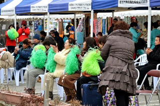 椅子に座った観客が緑のボンボンを持って拍手をしている写真