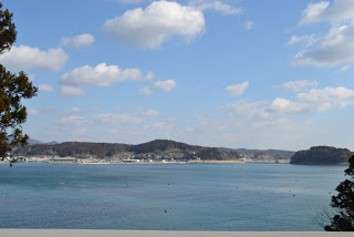 奥になだらかな山並みが見える、静かな湾の写真