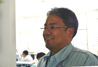 作業服を着た男性が笑顔で横を向いているアップ写真