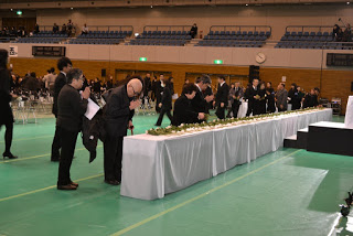 長い献花台にたくさんの参列者が次々に献花をし、手を合わせている様子の写真