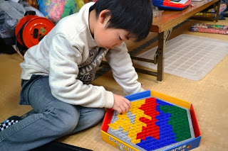 男の子が熱心にパズルブロックで図形を組み立てている遊びの様子を写した写真