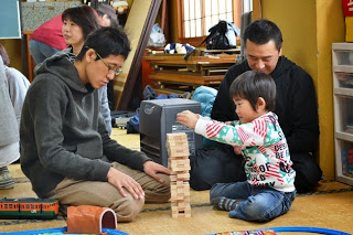 父親と子どもがジェンガの積み木ゲームに一緒に取り組み、積み木を高く積み上げて遊んでいる様子の写真