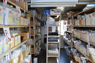 棚にラベルつけられ、分類された多数の写真が整然と並んでいるプレハブ内部の写真