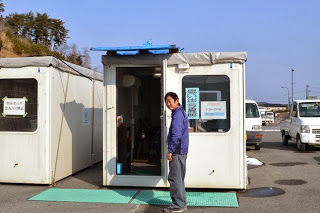 四角いコンテナの入り口の扉が開けられ、猪又隆弘センター長が扉の前に立って出迎えている様子の写真