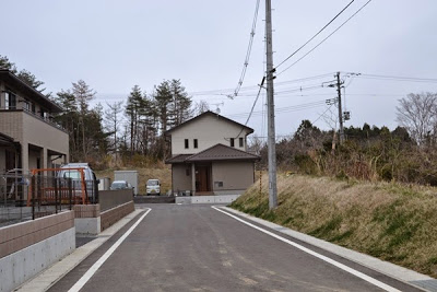 舗装された道の先や左側に新築の住宅が建っている新興住宅地の写真