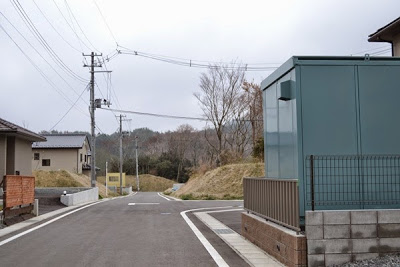 舗装道路沿いの両側に住宅が建っている新興住宅街の写真