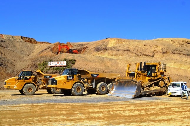 アーティキュレートダンプトラックが2台、黄色いブルドーザー、軽トラックが並び軽トラックと比較できるように並べられた写真