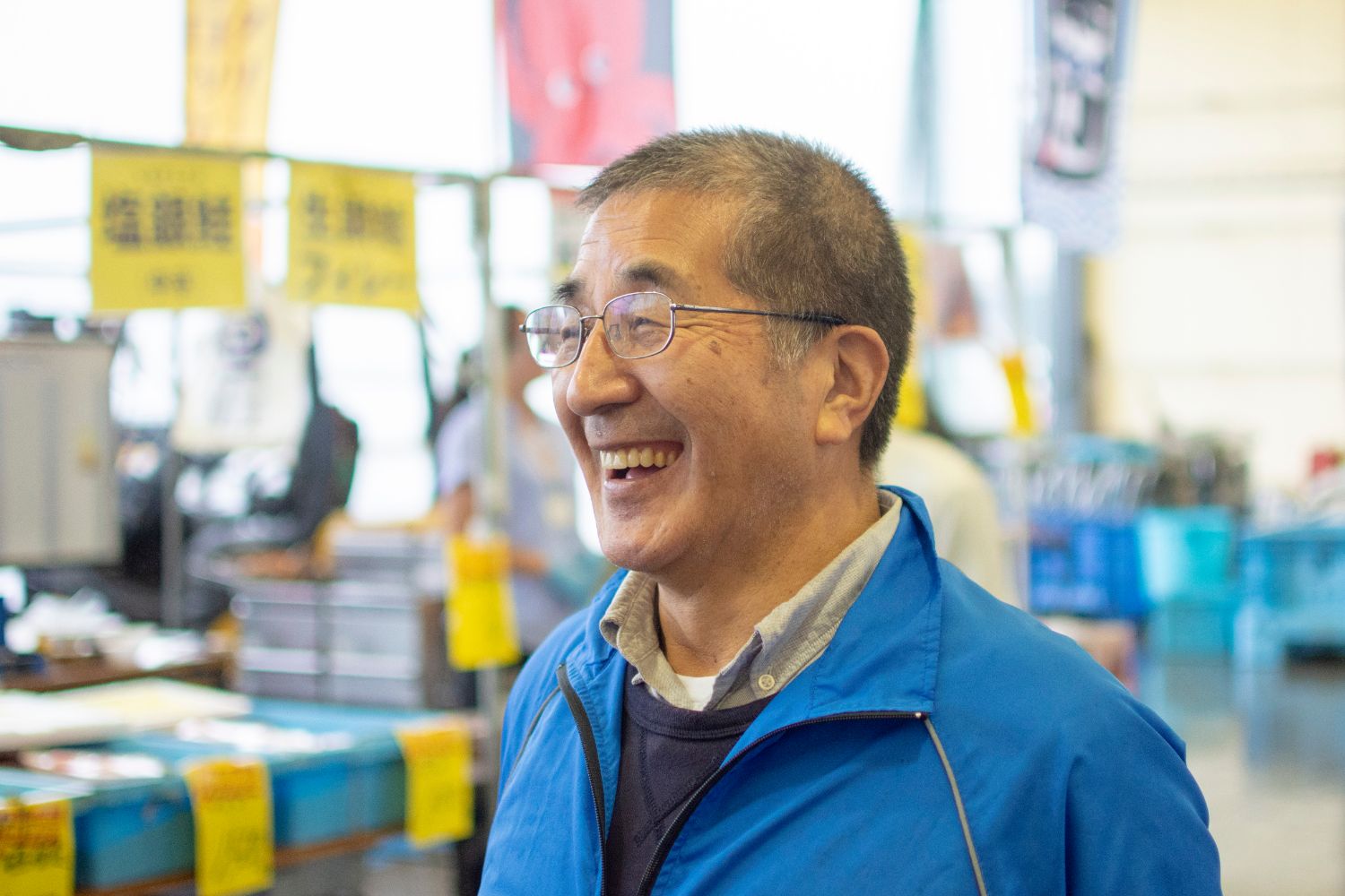 青いジャンパーを着た山内さんが笑顔で話をする様子の写真