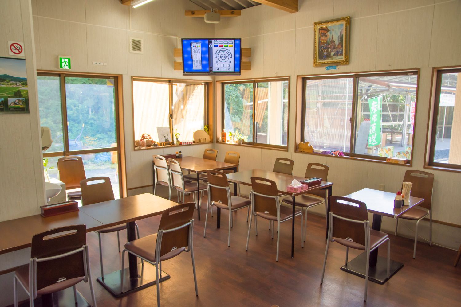 陽の光が差し込む窓際に面した店内には、2人掛けや4人掛けの椅子が並べられたテーブルが配置され、くつろげる雰囲気のカフェスペースの写真