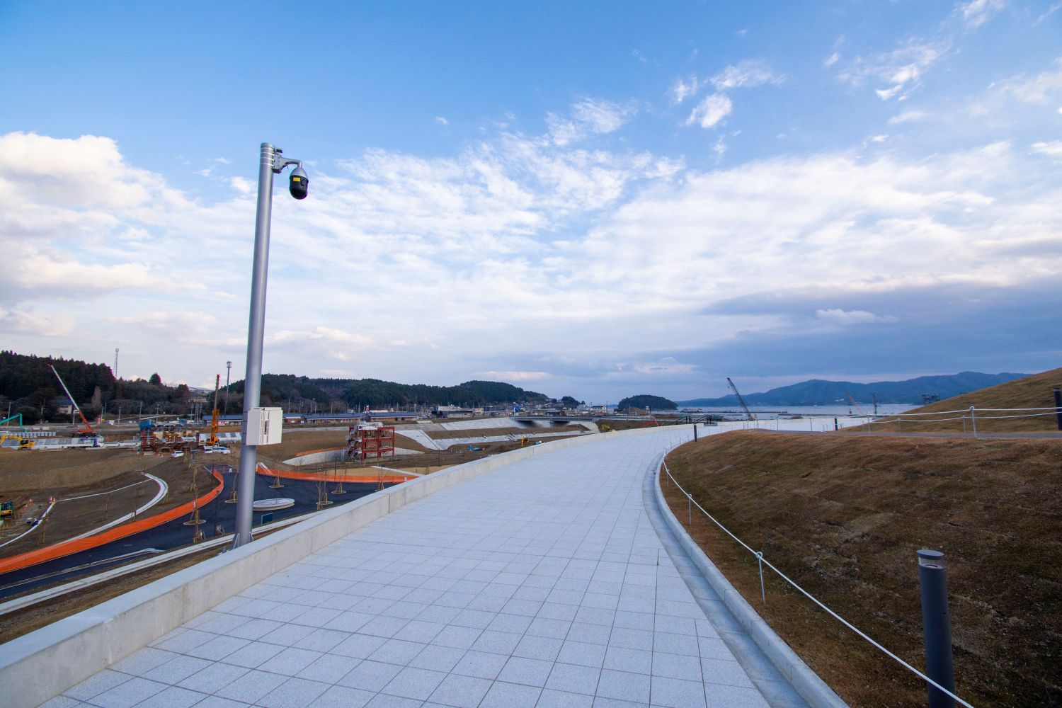 左側に津波の被害を受けた建物が保存され、広々とした開放的な風景の中に整備された遊歩道の写真