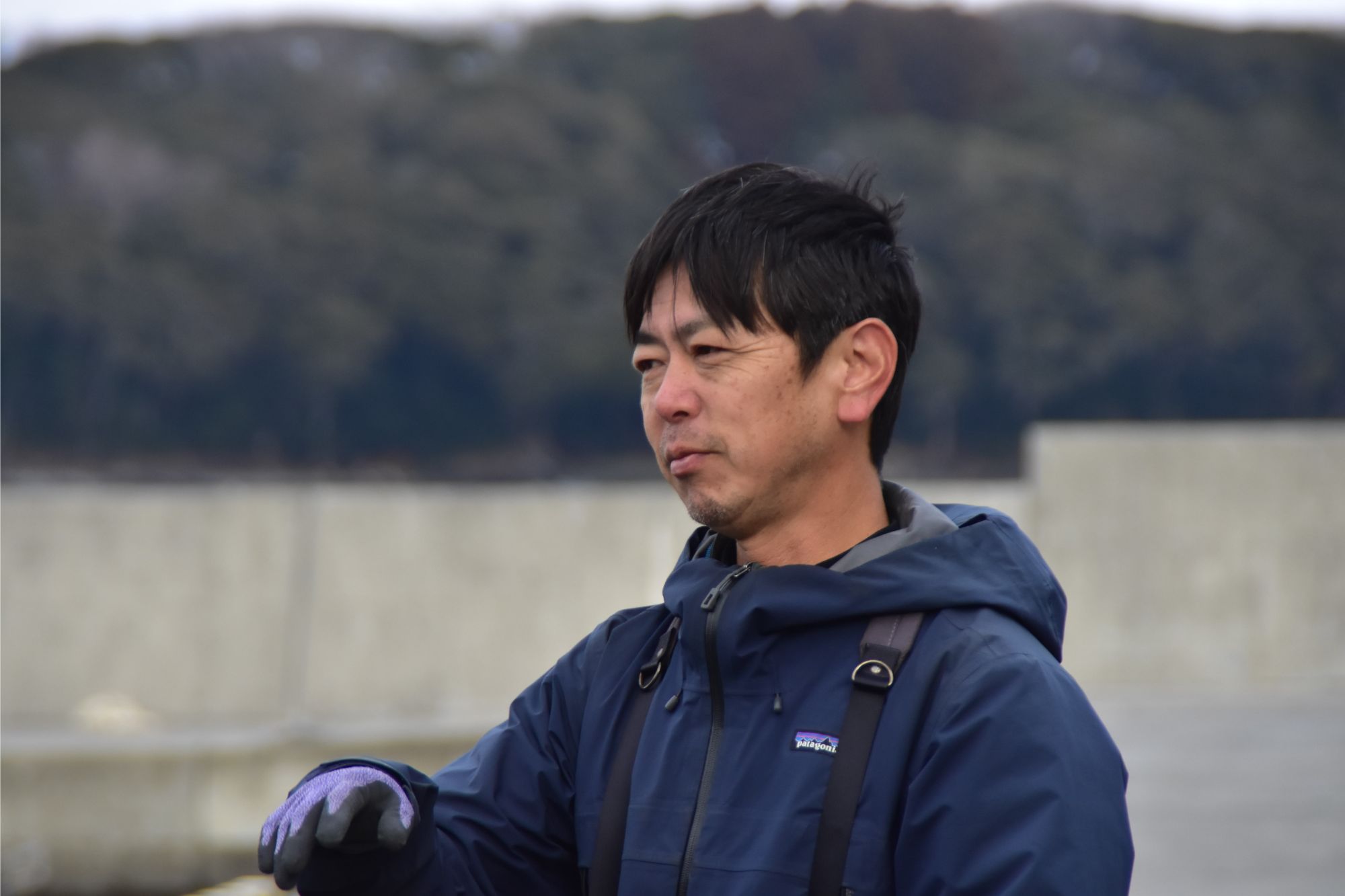 紺色のジャンパーを着た鈴木卓也さんがコクガンを眺めている様子の写真