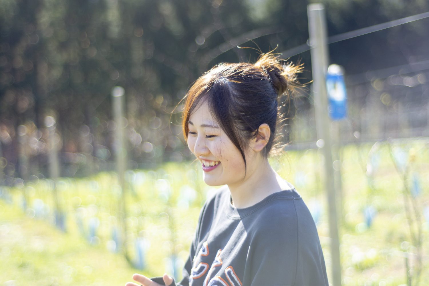 畑の中で立っている笑顔の大沼ほのかさんを横から撮影した写真