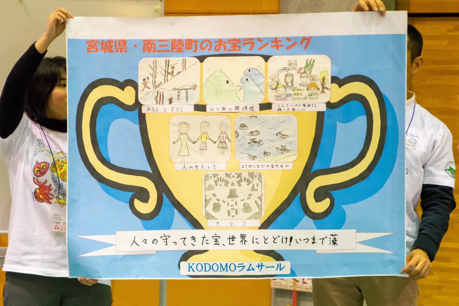 宮城県・南三陸町のお宝ランキングを紹介するポスターで、中央の金色のトロフィーの中に5つのイラストが描かれ、下部には「人々の守ってきた宝、世界にとどけいつまで藻」というメッセージが記されている写真