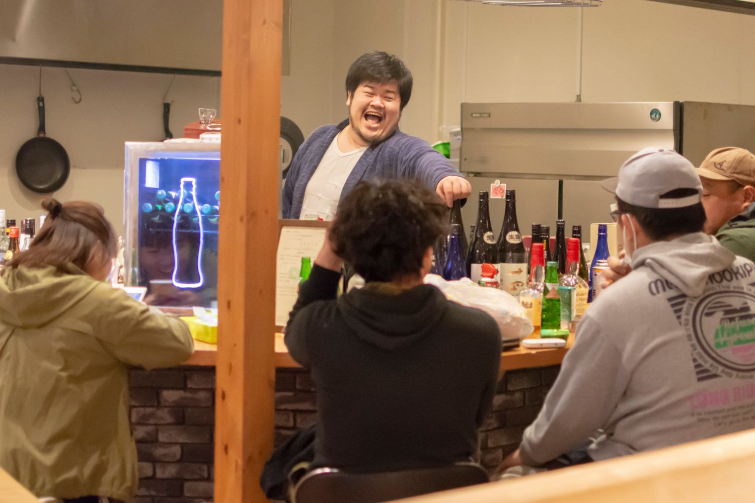 カウンターに座るお客さんたちと佐藤裕さんが楽しそうに談笑している写真