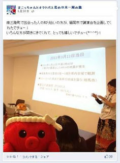 オクトパス君のぬいぐるみの後ろに室内でスクリーンに映された2011年3月11日の災害に関する資料を前に、講師の女性が説明をしている講演会の様子が写されたFacebookのページを写した写真