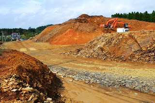 赤土の山の斜面でショベルカーが作業をしている、地盤の造成と整地作業が大規模に行われているのがわかる造成地全体の写真