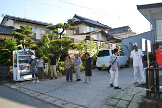 住宅街の一角で男女8人ほどの住民が集まってきている避難訓練の集合時の様子の写真