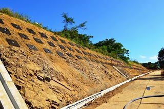 きれいに整えられた斜面にたくさんの黒いプレートが取り付けられていて、雨水を流すための溝も整備された法面補強工事の様子の写真
