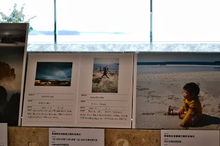 窓際に設置された棚に、子どもが砂浜で遊んでいる写真とその説明書きが並んでいる写真