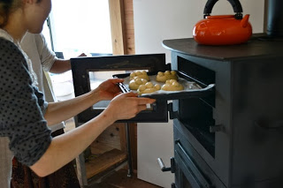 女性がオーブンにパン生地を乗せた天板を入れているところを横から撮影した、焼き始める場面の写真