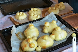 オーブンで焼き上がった、小さな丸が3つ乗った丸いパンがクッキングシートの上に並んでいる写真