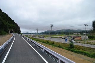 新しく舗装された車道が山のトンネルまで伸びている様子の写真