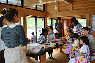 多くの参加者がテーブルの前に集まり、焼きあがったパンの試食しながら談笑している様子を写した写真