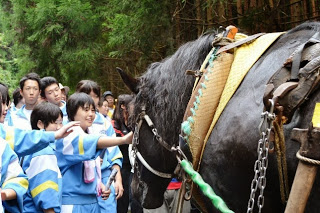 参加した生徒たちが黒い馬の顔を撫で、交流を楽しんでいる様子を写した写真