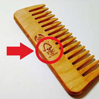 表面に赤い矢印と丸印でFSC認証のマークが示されている木製のくしの写真