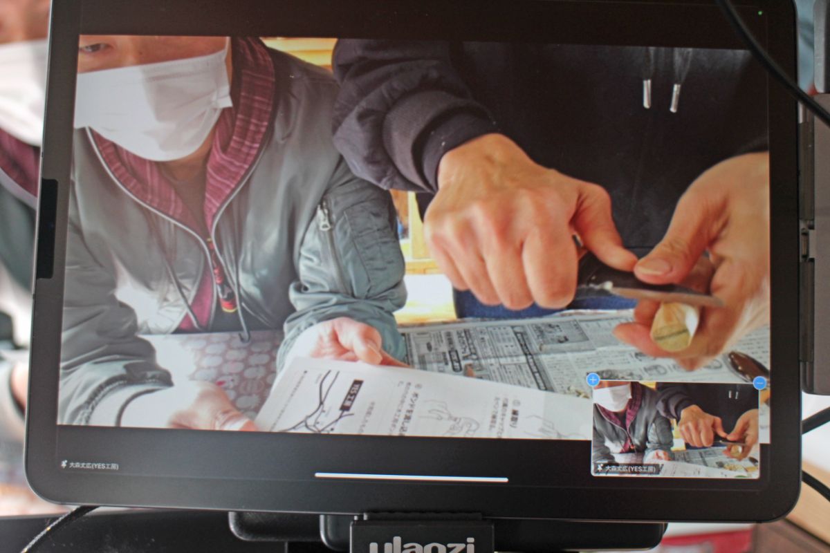 パソコンの画面に、木製の持ち手部分をナイフで削っている様子が映し出されている写真