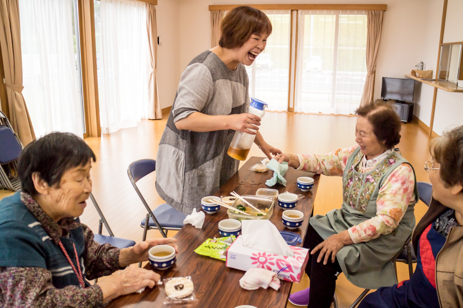 広々とした部屋でテーブルを囲み、お茶を飲みながら笑顔で談笑している4人の女性の写真