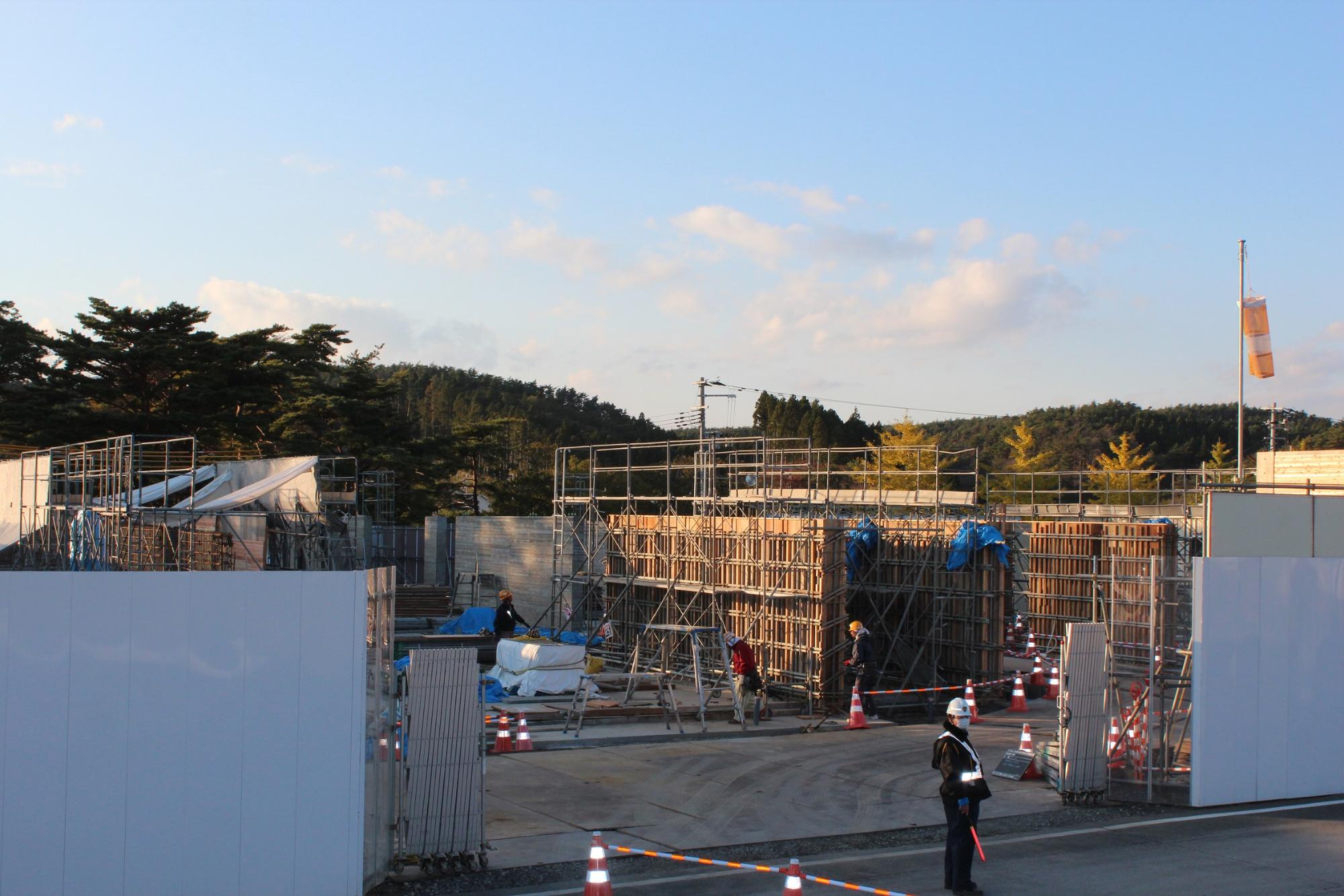 作業員が数名作業する中、鉄骨と型枠の組み立てが進んでいる建設中の写真