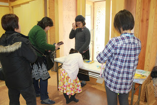 室内に置かれた白い長机の周りに4人の女性と1人の女の子が集まっている写真