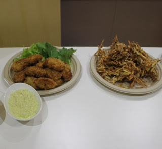 俵型のフライ料理が盛り付けられた大きな丸皿と、かき揚げが盛り付けられた大きな丸皿が並び、その前にタルタルソース風のソースが添えられている写真