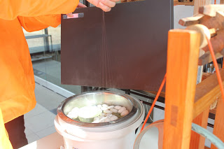 湯気の上がったお湯にたくさんの白い繭玉が入っており、そこから細い糸を数本まとめて引き上げている様子の写真