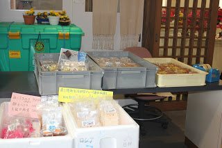 お菓子などが入った発泡スチロールやプラスチックの箱が5つ台の上に置かれている写真