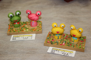 緑とピンクの2匹のカエルの作品、2匹の黄色いカエルの作品が2つ並んでいる写真