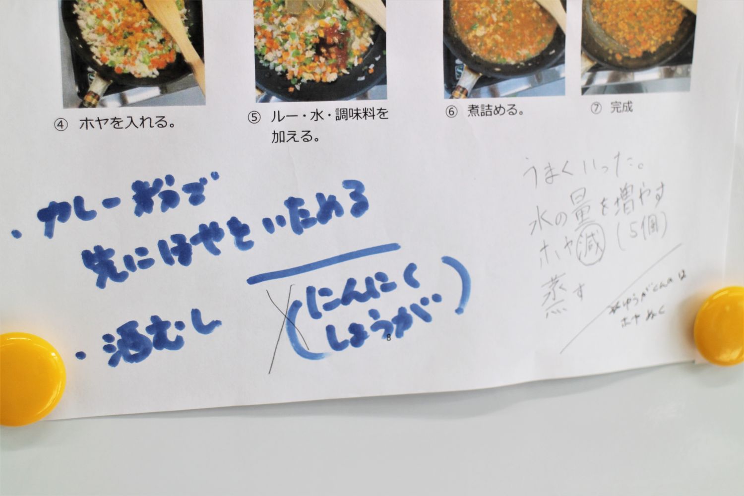 具材や手順に関する手書きのメモやコメントが青と黒のペンで書き込まれている、料理手順の紙が写真付きで掲示されている写真