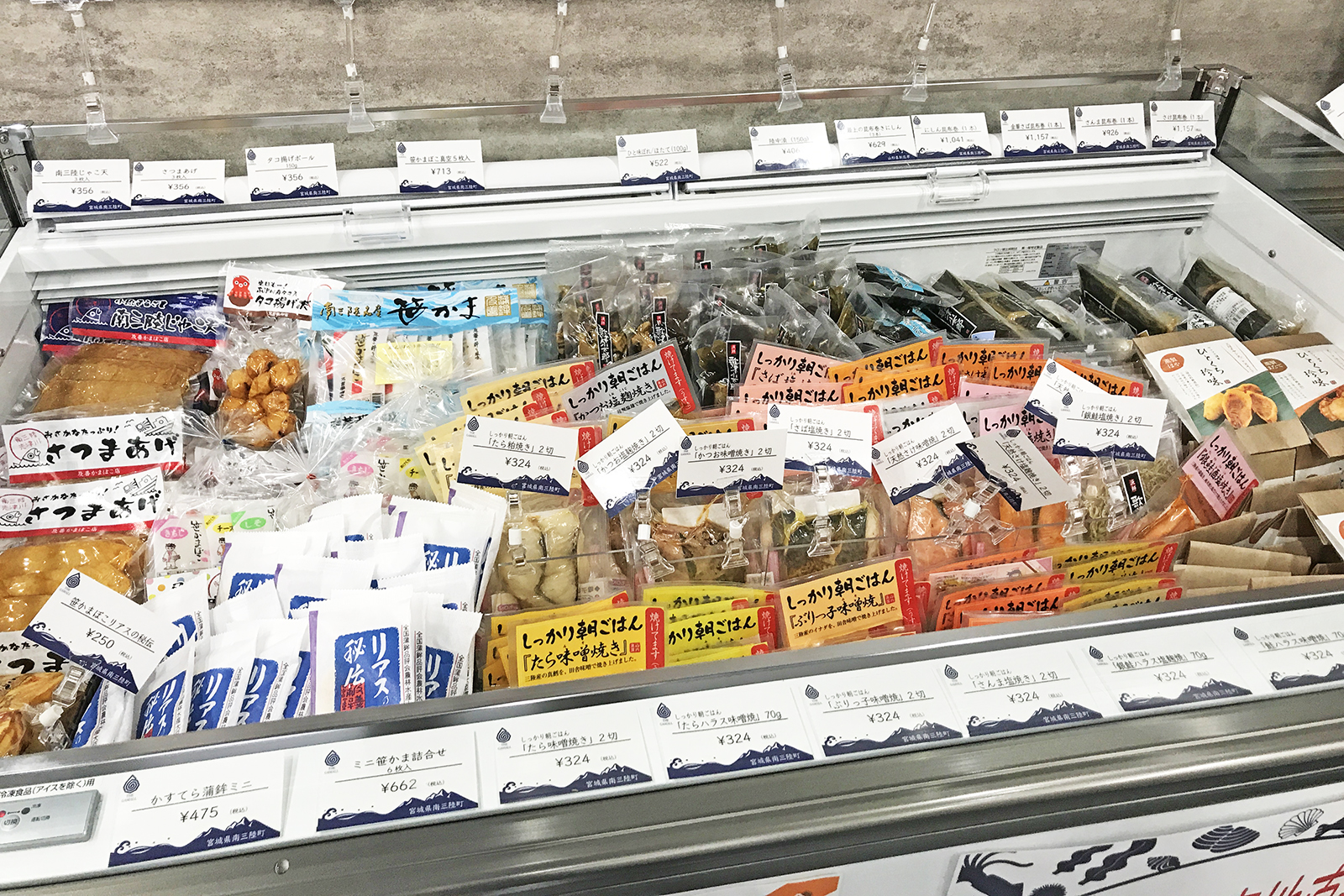 冷蔵のショーケースに袋詰めされた魚介加工品などがぎっしり陳列されている写真