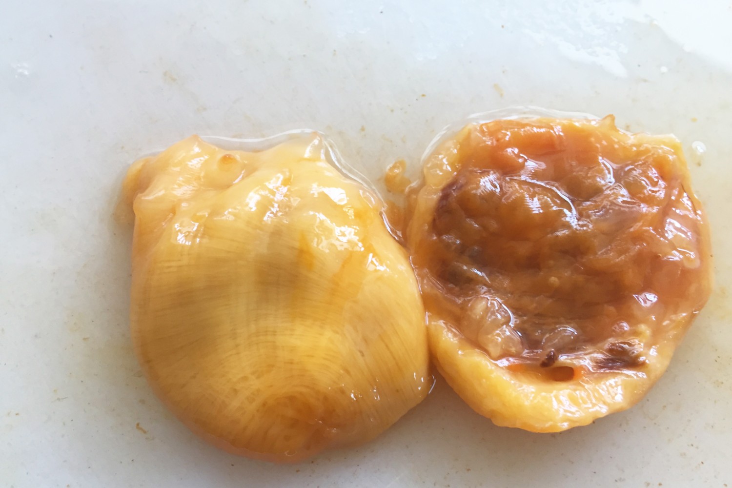 皮を外し黄色い身と茶色い内臓部分をそれぞれ並べて白いまな板の上に置いた状態を写したホヤの中身の写真