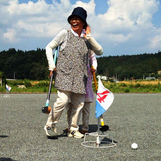 旗に4と書かれたホールポストと外れた位置に止まっている白いボールの傍で、黒い帽子を被った女性が右手でクラブを持ち笑顔で喜んでいる写真