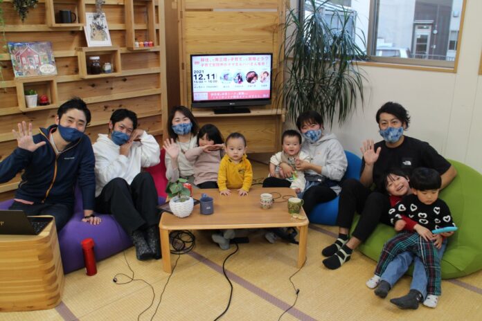 木の棚と畳敷きの温かみのある室内で、子ども連れの親子が笑顔で手を振っている様子を写した写真