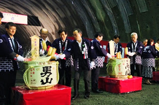 トンネル内で法被を着た関係者たちが、木槌で酒樽を割っている鏡開きの様子の写真