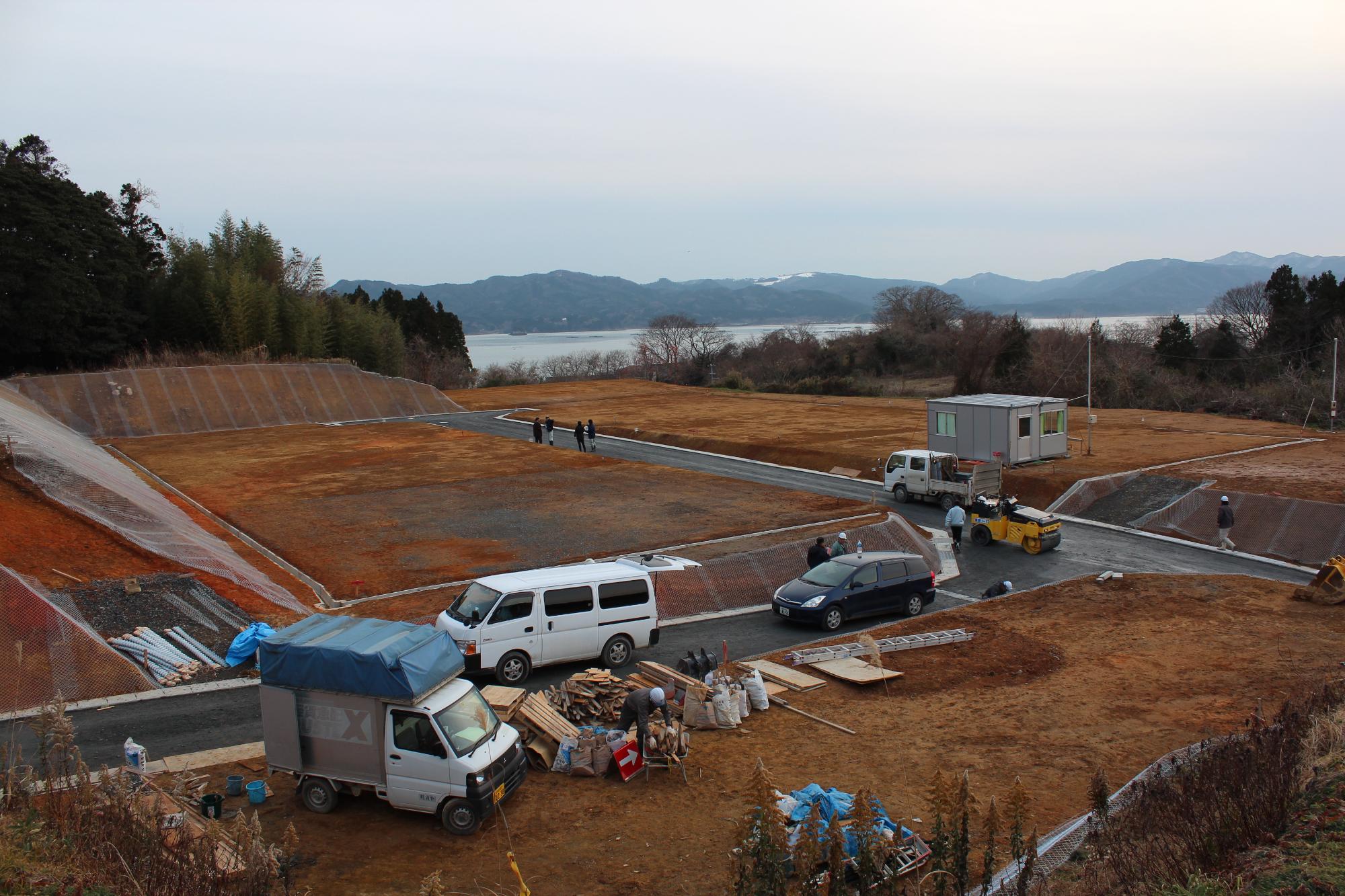 整地が終わりアスファルトの道路が敷かれ、敷地が区画された造成地に数人が立ち合い確認をしている様子の写真
