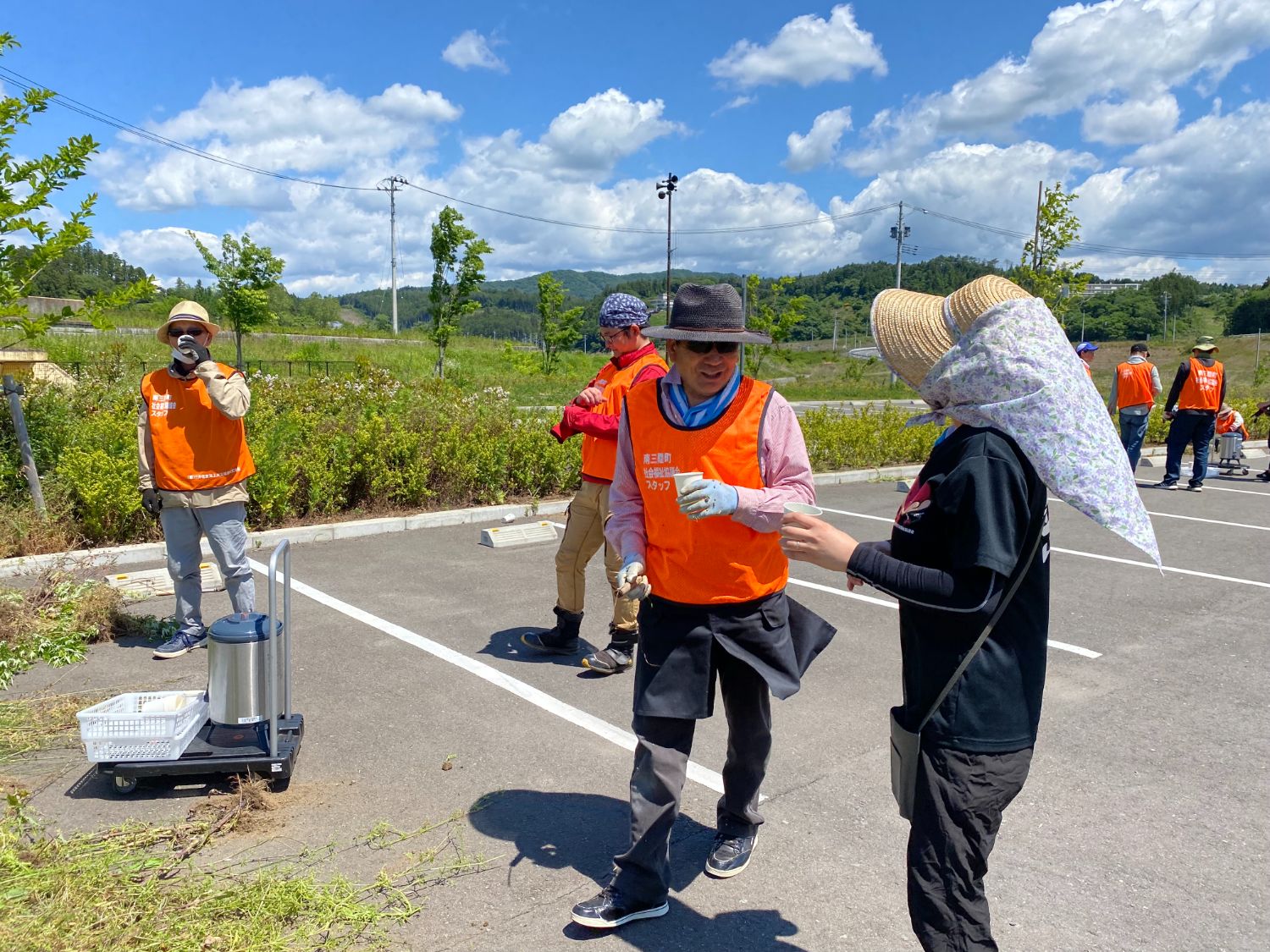 作業の合間に飲み物を手にして会話をしている人たちの休憩している様子の写真