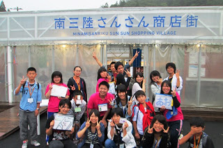 ワークショップ参加者の子どもたちとスタッフが集合し、笑顔でカメラに向かってポーズをとっている集合写真