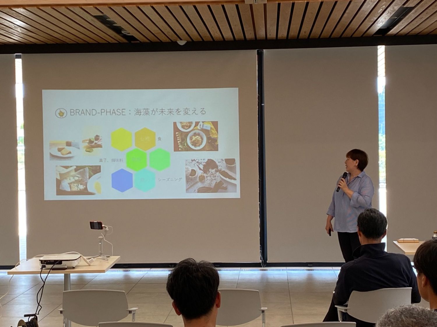 山口さんがマイクを持ち、「海藻が未来を変える」というスライドを使ってプレゼンテーションを行っている写真