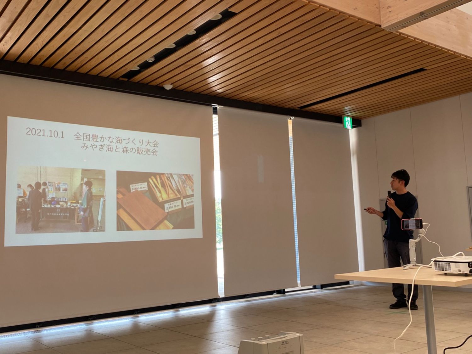 太田さんがマイクを持ち、スライドを使ってプレゼンテーションを行っている写真