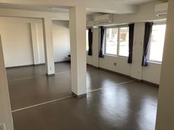 柱で区切られた広めの室内に窓が複数あり、カーテンが取り付けられたシンプルな多目的ルームの写真